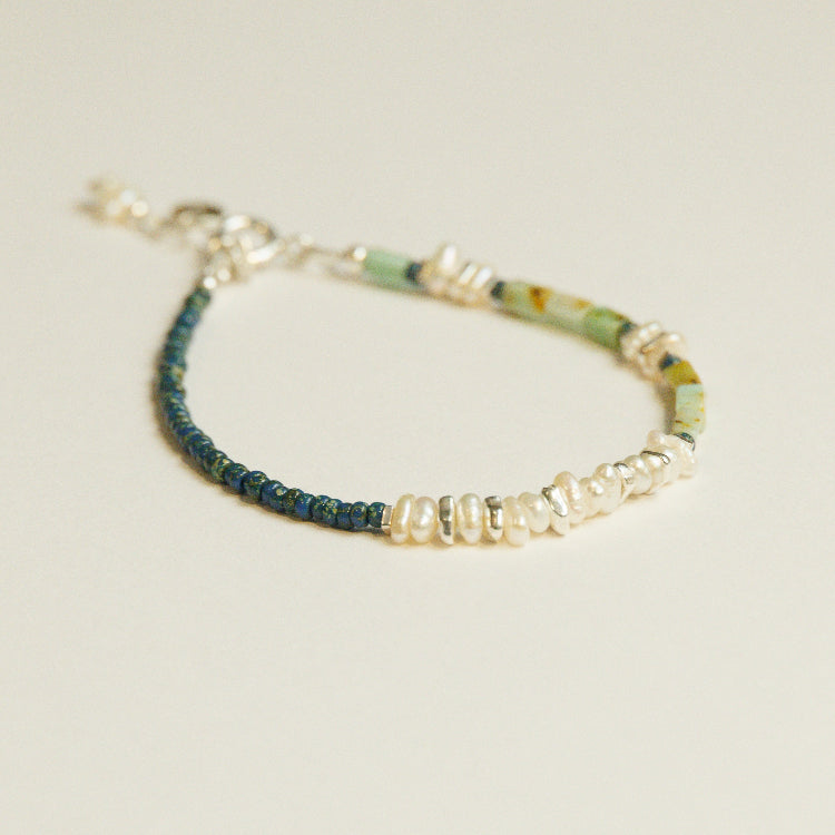 Detail van parels en chrysoberyl in een asymmetrische kralenarmband met zilveren elementen.