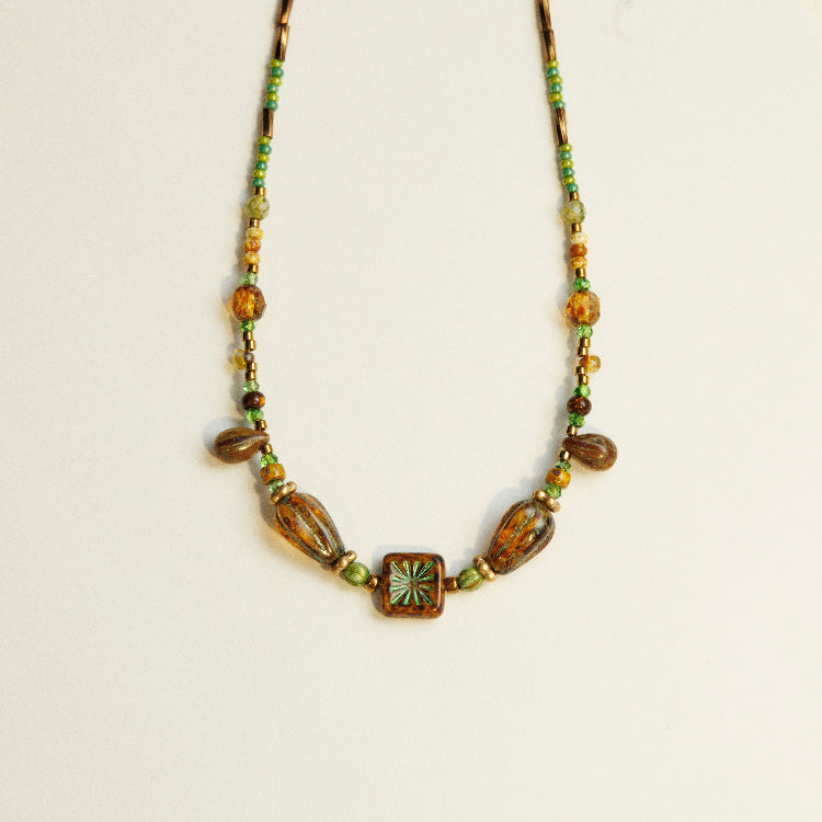 Antieke kralenketting van Tsjechisch glas gedragen rond de hals, met rijke textuur en kleurcontrast
