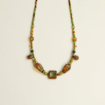 Antieke kralenketting van Tsjechisch glas gedragen rond de hals, met rijke textuur en kleurcontrast