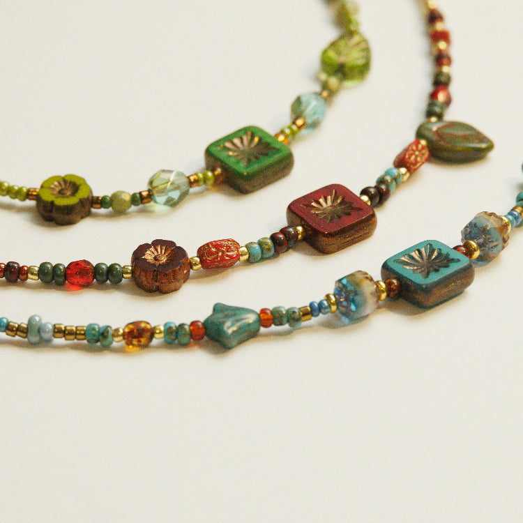 Detail van rood, turquoise en groen glaskralen in een handgeregen driekleurige armbandenset