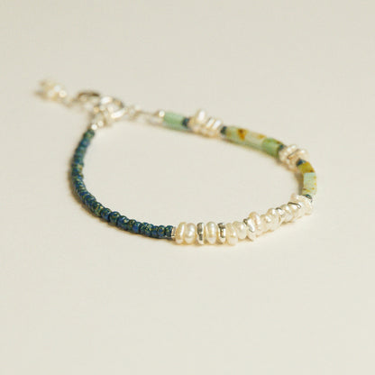 Detail van parels en chrysoberyl in een asymmetrische kralenarmband met zilveren elementen.