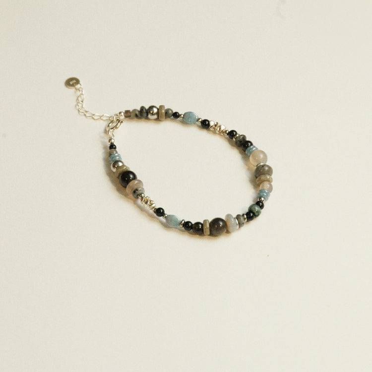 Detail van zwarte agaat en labradoriet stenen in een kralenarmband, met zilveren accenten