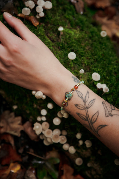 model draagt een kralen armband in de natuur