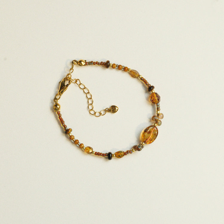 Handgemaakte kralenarmband van tijgeroog en glas met koffieboonvormige kraal, in warme aardetinten.